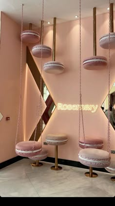 a pink room with hanging chairs and mirrors on the wall that says rosemary in gold letters