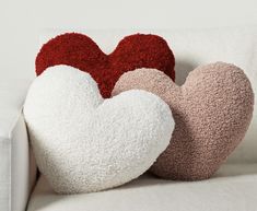 two heart shaped pillows sitting on top of a white couch