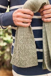 a person holding two knitted mittens in their hands and wearing striped sweaters