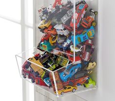 a clear box filled with assorted toy cars sitting on top of a white door