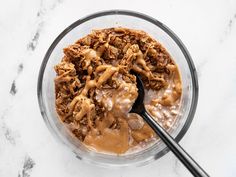 an oatmeal dish with peanut butter and other toppings in a glass bowl