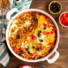 a casserole dish with beans, cheese and other toppings on a wooden table