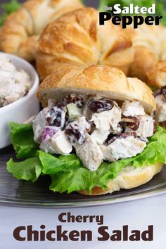 a chicken salad sandwich on a croissant bun with lettuce and olives