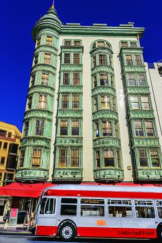 a red and white bus parked in front of a tall building on a city street