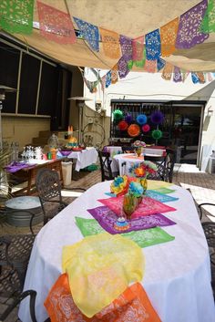 the table is covered with colorful cloths and place settings for guests to sit at