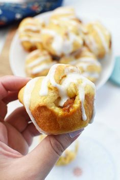 a hand holding a pastry with icing on it