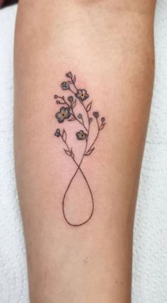 a small tattoo on the leg of a woman with flowers in her hand and an arrow