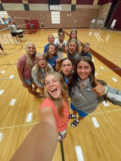 a group of young women standing on top of a basketball court holding their thumbs up