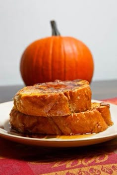 two pieces of bread on a plate with a pumpkin in the background