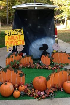 pumpkins are arranged in front of a van with a sign that says welcome great pumpkin