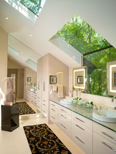 a large bathroom with two sinks and a skylight in the ceiling, along with an area rug on the floor