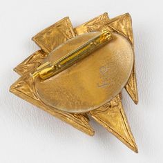 It is a striking Talosel or resin pin brooch designed by Irena Jaworska in the 1970s.  The piece features a dimensional geometric modernist shape in gilded resin framing, topped with triangle mirrors in yellow and burnt orange colors. The pin is marked underside with the artist's monogram signature. Irena Jaworska is one of the Line Vautrin School students whose work has been identified and recognized in the 1960s-1970s. Measurements: 2.44 in. wide (6.2 cm) x 2.69 in. high (6.8 cm).  Please see Triangle Mirror, Line Vautrin, Burnt Orange Color, Best Wear, The 1970s, School Students, Pin Brooch, The Line, Burnt Orange