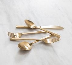 three forks and two spoons on a marble surface