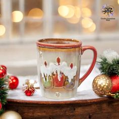 a coffee mug sitting on top of a wooden table next to christmas decorations and baubles