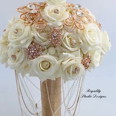 a bridal bouquet with white roses and pearls on the bottom is adorned with jewels