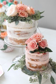 two wedding cakes with flowers on top are sitting on the table next to each other