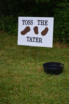 a sign that says toss the tater next to a black bucket on some grass