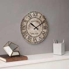 a clock that is on the wall next to a mirror and pen holder with pens