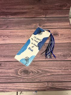 a blue bookmark with writing on it sitting on top of a wooden table