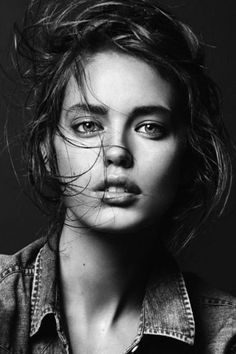 a black and white photo of a woman with her hair blowing in the wind, wearing a denim shirt