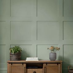 a wooden table with two baskets on it and a plant in the corner next to it