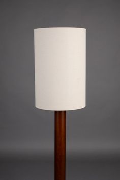 a table lamp with a white shade on it's base and a wooden stand