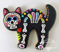 a black cat with colorful sugar skulls on it's face is shown in this image