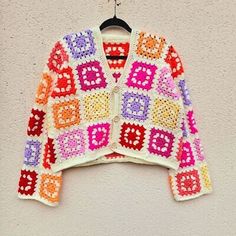 a colorful crocheted sweater hanging on a wall