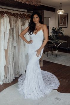 a woman standing in front of a rack of wedding dresses