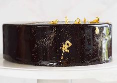 a black and gold decorated cake on a white table with sprinkles all over it