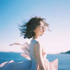 a woman in a white dress standing by the ocean