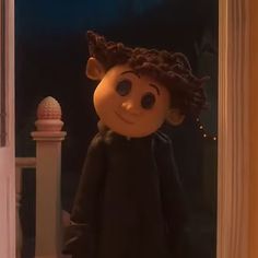 a doll is standing in front of a door with its eyes wide open and it looks like she's smiling