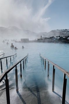 people are swimming in the blue lagoon on a sunny day with steam rising from the water