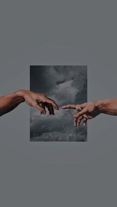 two hands reaching out towards each other in front of a cloudy sky with dark clouds