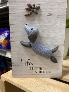 a wooden sign with a sea lion and starfish on it that says life is better with a dog