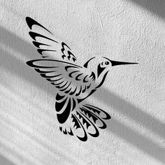 a black and white photo of a bird on the side of a building with its wings spread