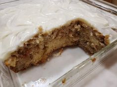 a partially eaten cake with white frosting in a glass dish on a counter top