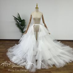 a mannequin wearing a white wedding dress with long tulle skirt on display