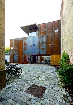 two bikes are parked in front of an old building with rusted metal panels on it