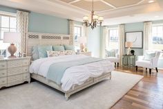 a bedroom with blue walls, white furniture and a chandelier hanging from the ceiling