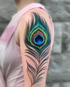 a peacock feather tattoo on the arm