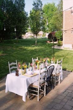 a table set up outside with flowers and candles on it