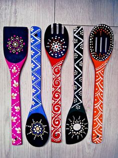 five colorful spoons with designs on them are lined up in a row against a white background