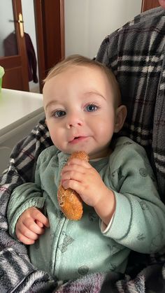 a baby sitting in a high chair eating a donut