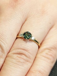 a woman's hand with a ring on it and a green stone in the middle