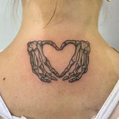 two hands making a heart shape tattoo on the back of a woman's neck