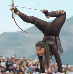 a woman standing on one leg while holding an arrow