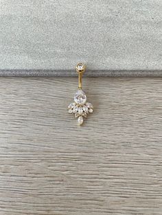 a pair of gold and diamond earrings on a wooden surface, with the earring in the shape of a snowflake