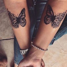 two people holding hands with butterfly tattoos on their arms