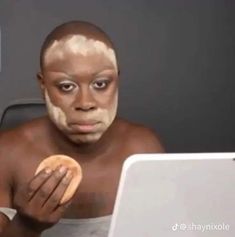 a man with his face painted white and holding a doughnut in front of him